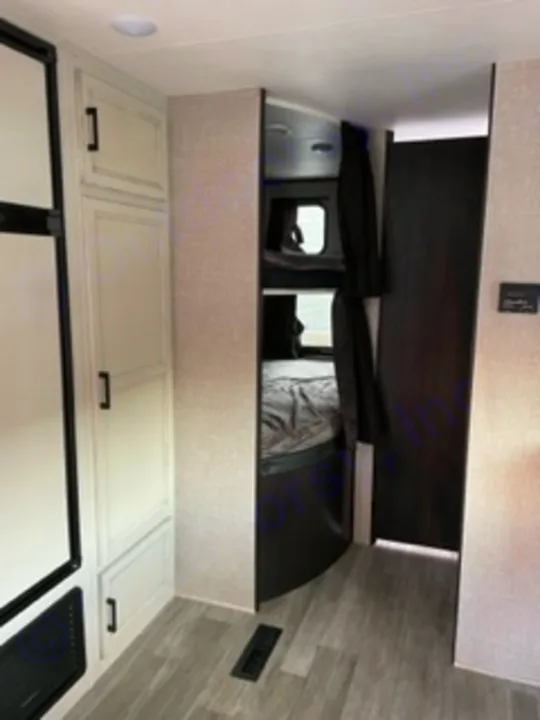 View inside an RV rental showing modern bunk beds with dark curtains and white storage cabinets.. Jayco Jay Flight SLX 8 2023