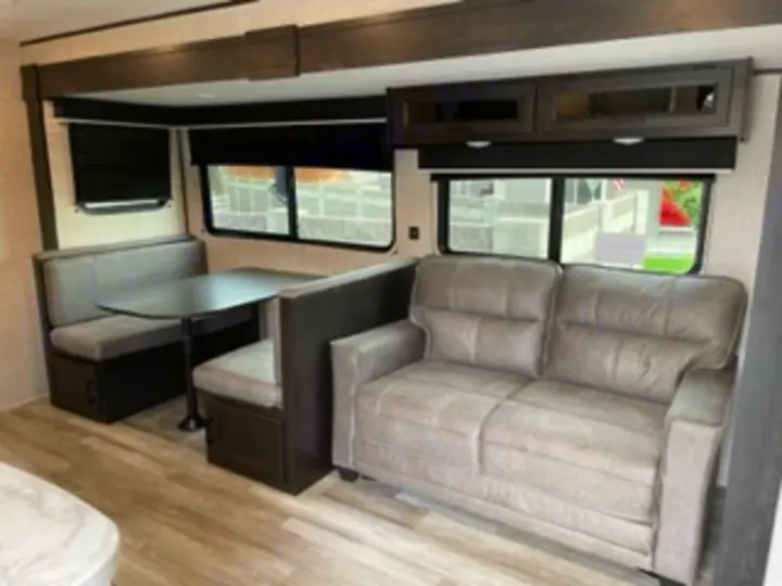 This spacious RV rental features a comfortable gray sofa and a dinette with bench seating for dining, ideal for relaxing after adventures.. Jayco Jay Flight SLX 8 2023