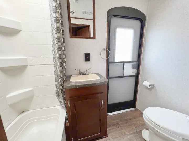 An RV rental bathroom showing a shower/tub, vanity sink, toilet, and entry door, all in a compact space.. Jayco Jay Flight 2016