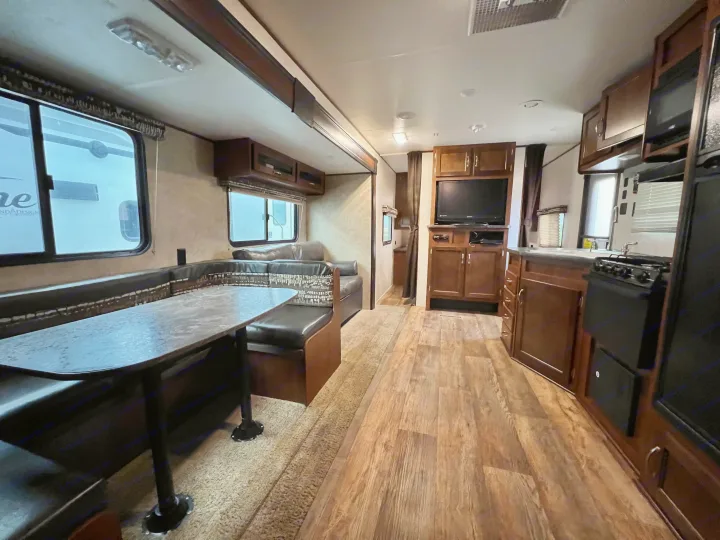 Inside a travel trailer rv rental, showcasing a comfortable dining booth, kitchen, and TV setup.. Jayco Jay Flight 2016