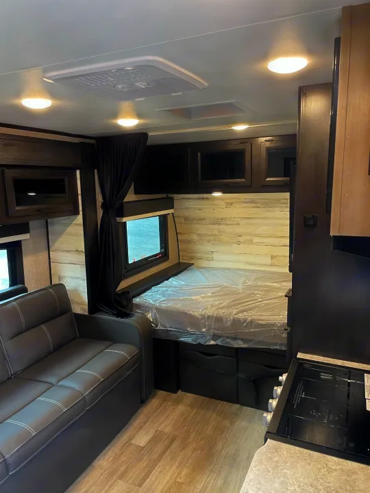 RV rental interior: modern living area with sofa, bed, kitchen, and overhead storage. Well-lit and compact space.. Jayco Jay Feather Micro 2022