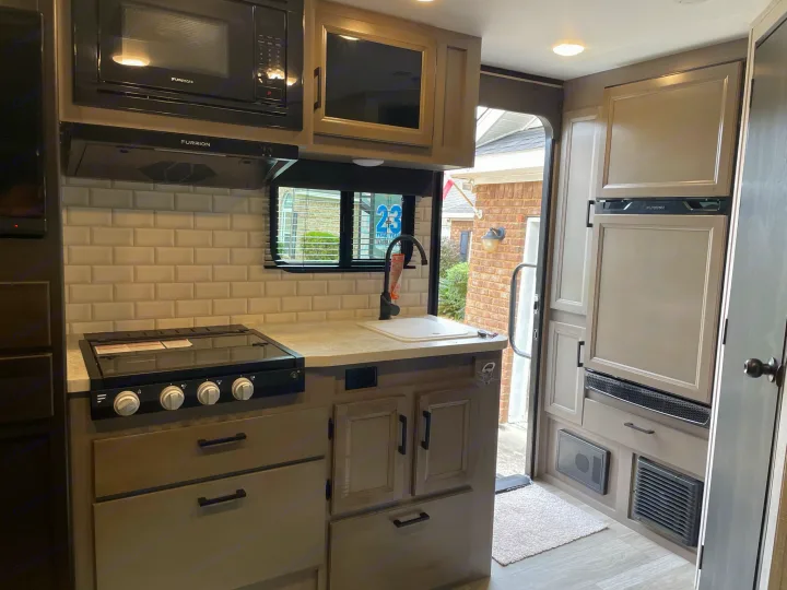 Modern RV rental kitchen with microwave, stove, sink, and refrigerator. Fully equipped for your adventure.. Jayco Jay Feather Micro 2022