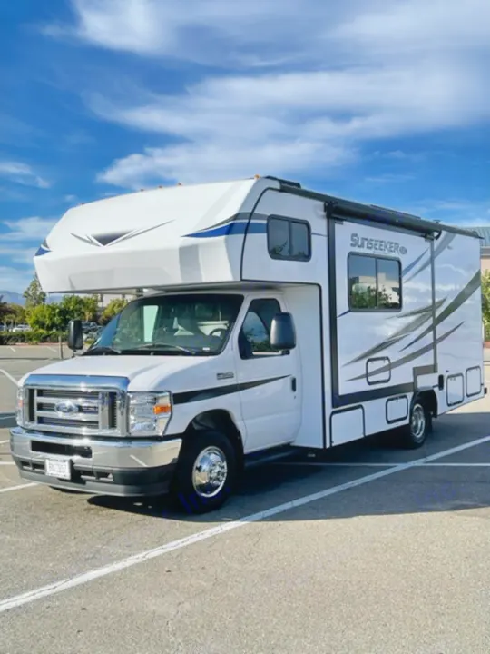 A white Class C Sunseeker RV rental is parked in a lot under a blue sky, ready for adventure.. Forest River Sunseeker LE 2022