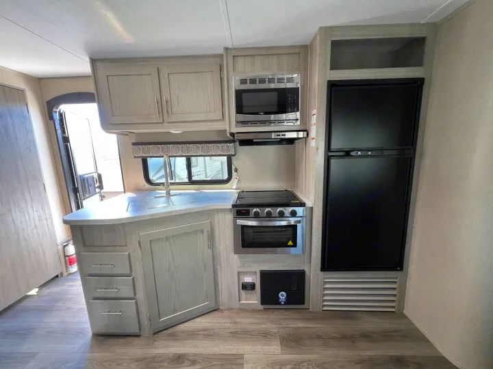 Well-equipped RV rental kitchen: sink, stove, microwave, fridge, & light cabinetry.. Coachmen Catalina 2022