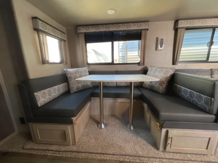Cozy RV rental dinette: U-shaped seating, center table, and large windows.. Coachmen Catalina 2022