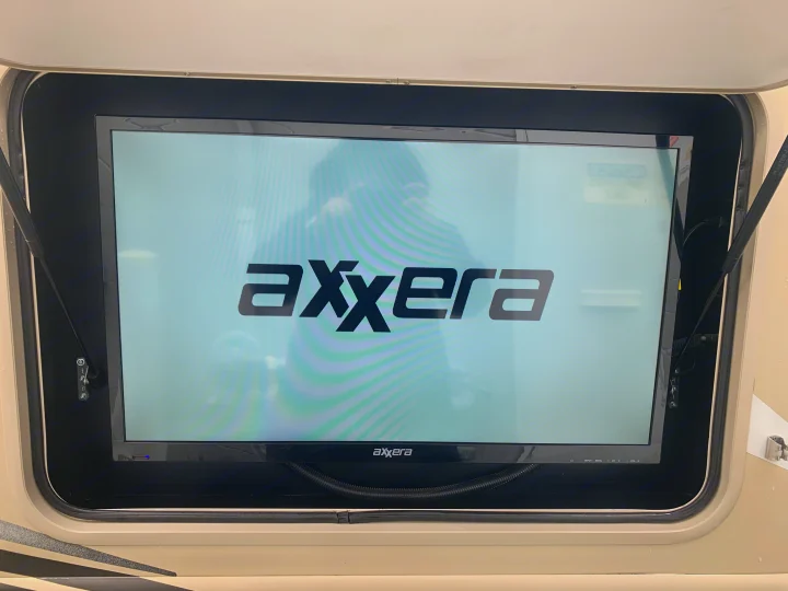 Axxera outdoor TV mounted in an RV rental bay, displaying its logo.. Thor Motor Coach Chateau Sprinter 2018