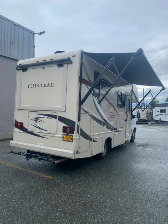 A beige Chateau RV rental is ready for adventure, with its awning extended, LED lights, and a rear bike rack.. Thor Motor Coach Chateau Sprinter 2018