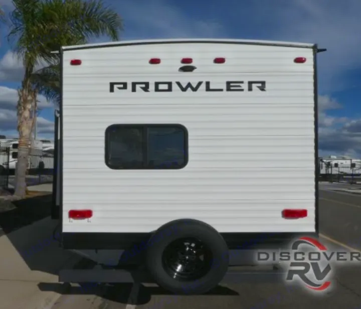 Rear view of a white Prowler travel trailer RV rental, showing a spare tire, rear window, and red lights.. Heartland Prowler 2022