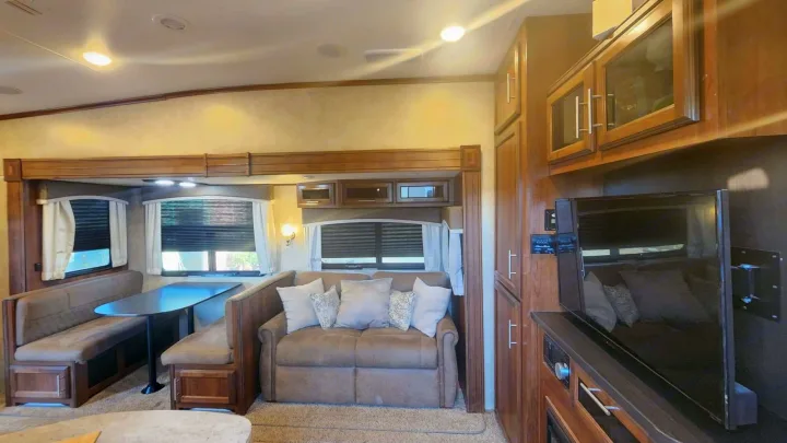 Spacious RV rental living area features a comfortable dinette, sofa, wall-mounted TV, and ample storage.. Jayco Eagle HT 2018