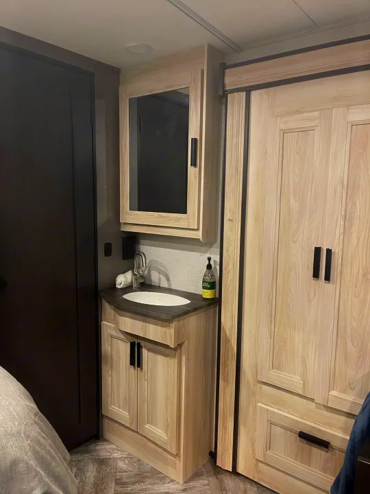 RV rental: Compact bathroom vanity with sink & medicine cabinet, alongside a light wood wardrobe. Functional interior for travel.. Forest River Sunseeker LE 2022