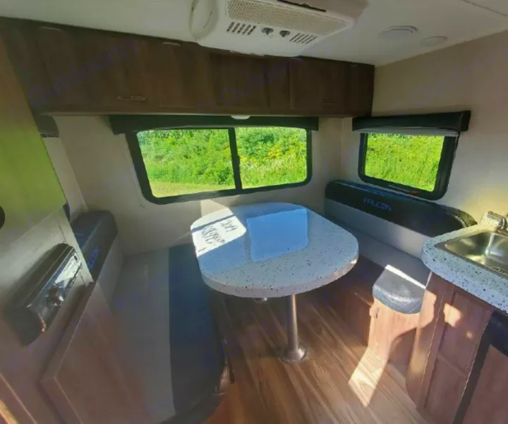 An RV interior showing a bright dinette with table, bench seating, and kitchen sink, ideal for an rv rental.. Travel Lite Falcon 2019