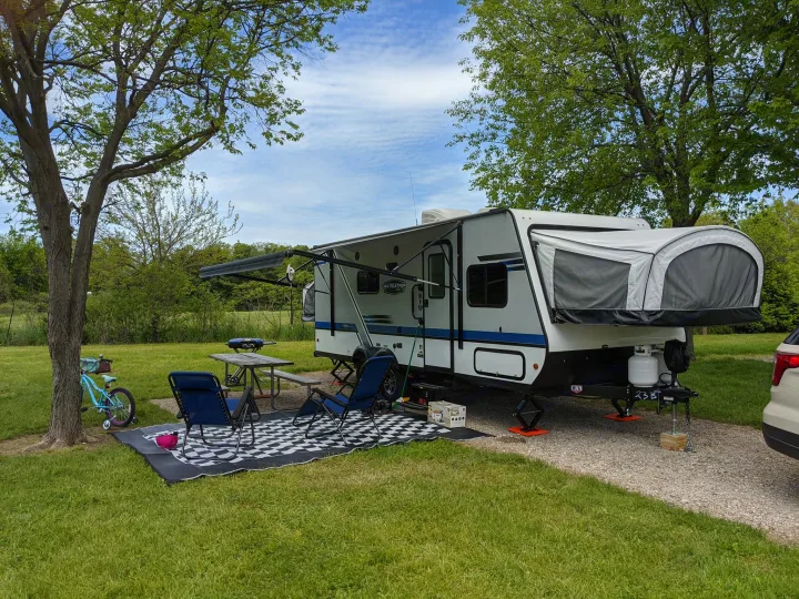 Relaxing at a scenic RV rental campsite: travel trailer with awning, picnic spot, and bicycle on green grass.. Jayco Jay Feather 2019