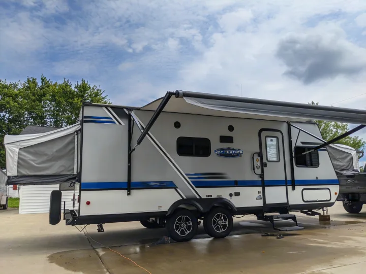 Grey/white Jay Feather travel trailer RV rental with extended awning & rear pop-out, parked on concrete.. Jayco Jay Feather 2019