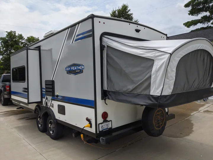 Considering an RV rental? This grey and white Jayco Jay Feather hybrid travel trailer features a pop-out bed and rear spare tire.. Jayco Jay Feather 2019
