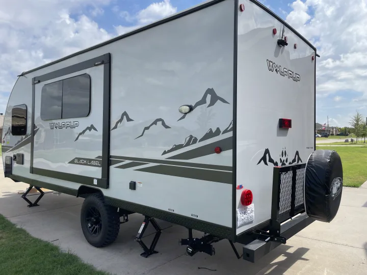 A sleek, light gray Forest River Wolf Pup travel trailer, set up with stabilizers, perfect for your next RV rental adventure.. Forest River Cherokee Wolf Pup Black Label 2022