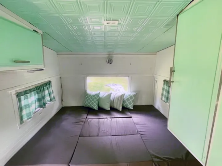 Experience comfort in this RV rental's mint green & white interior, featuring a convertible bed and stylish ceiling tiles.. Shasta Compact 1973