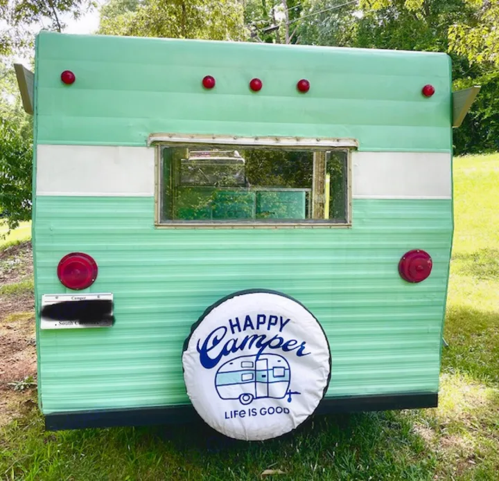 Retro green & white RV camper, rear view with "Happy Camper" tire cover. Perfect rv rental for your next adventure!. Shasta Compact 1973