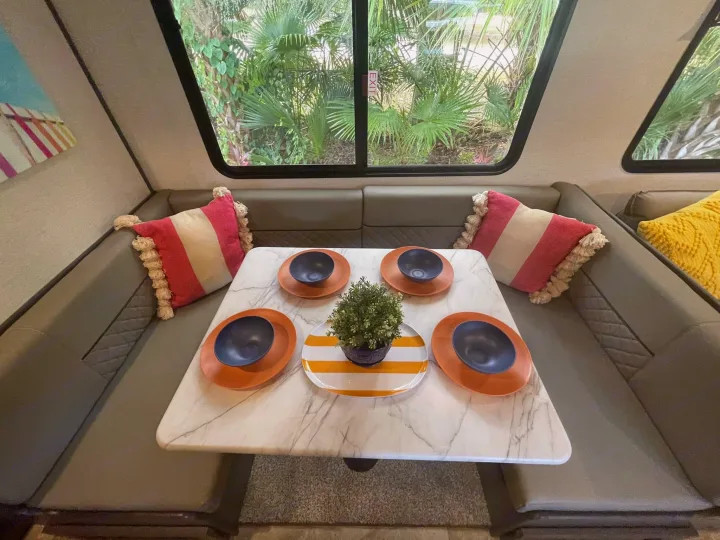 Cozy RV rental dinette: a comfy dining area with a set table and scenic green views, perfect for road trip meals.. Dutchmen Aspen Trail 2022