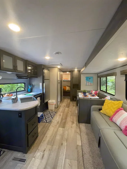 Modern RV rental interior with a spacious kitchen, dining area, sofa, and bunks. Ideal for travel accommodation.. Dutchmen Aspen Trail 2022