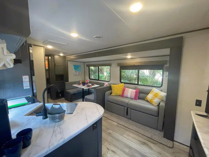 Explore this comfy RV rental interior! Features a well-appointed kitchen, spacious dinette, and cozy sofa with large windows.. Dutchmen Aspen Trail 2022