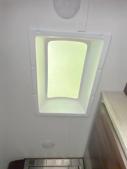 Bright RV rental interior showcasing a ceiling skylight, lighting, and upper cabinetry, offering natural illumination.. Travel Lite Falcon 2019