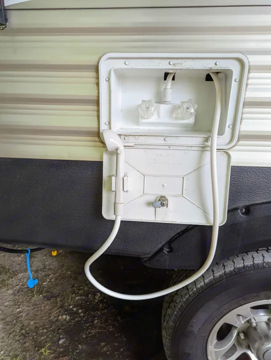 RV rental outdoor shower with winterizing instructions, showing hose, shower head, and water knobs for camper maintenance.. Keystone RV Springdale 2013