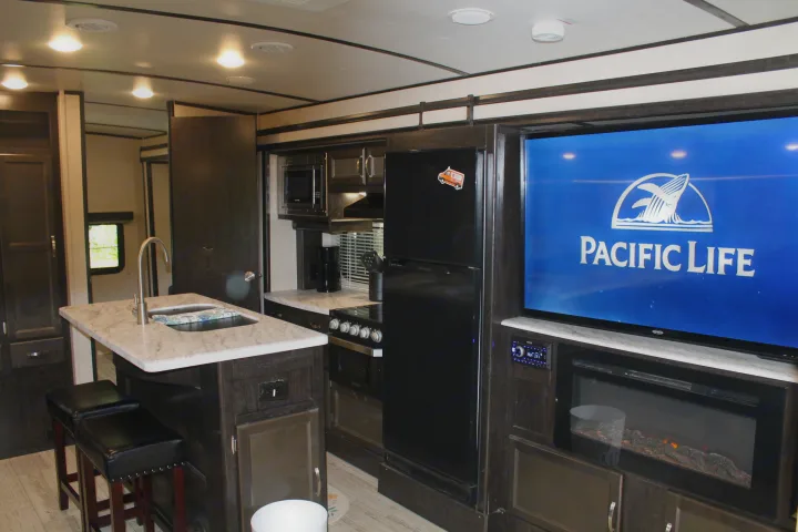 This modern rv rental interior boasts a well-equipped kitchen island, full appliances, and a comfy living space with TV & fireplace.. Coachmen Spirit Ultralight 2020