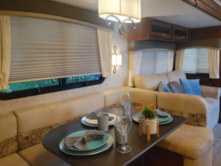 This comfy RV rental interior features a cozy dining booth with a set table, perfect for travel adventures.. Jayco Eagle 2016
