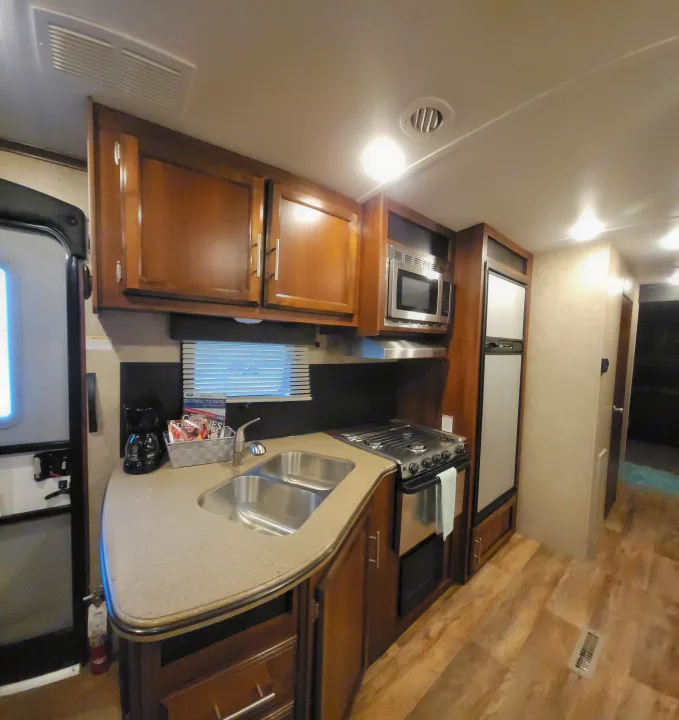 Spacious RV rental kitchen with double sink, microwave, stove, and fridge, perfect for your next adventure.. Jayco Eagle 2016