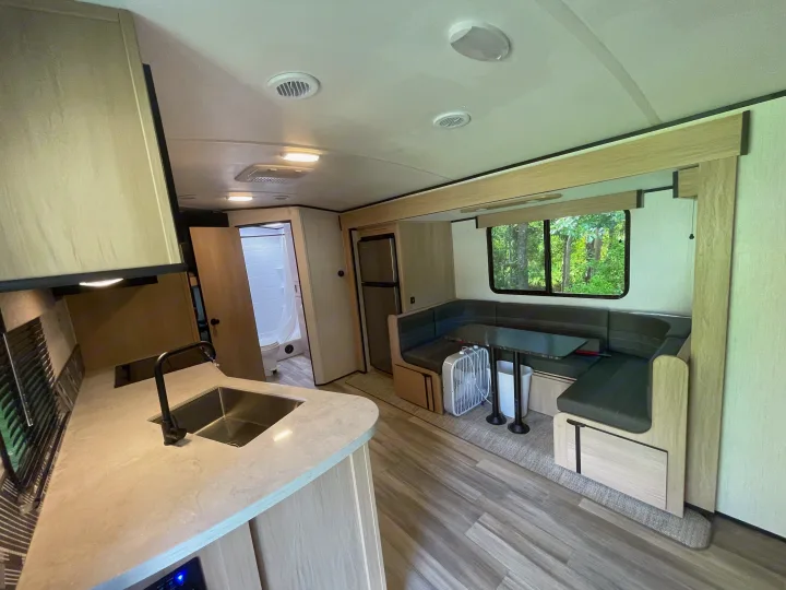 Comfortable RV rental interior: modern kitchen, dinette, bathroom, and fridge. Features wood-look floors & large window.. Cruiser Rv Corp Radiance 2022