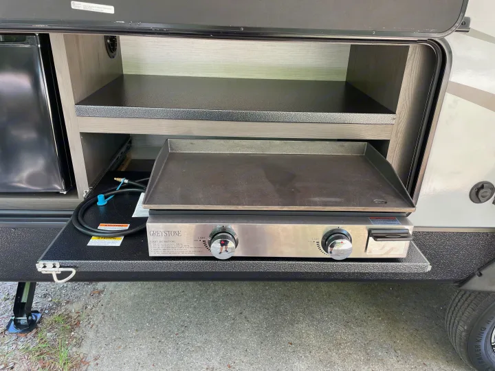 This rv rental's outdoor kitchen features a pull-out counter with a Greystone griddle and a mini-fridge for camping.. Cruiser Rv Corp Radiance 2022