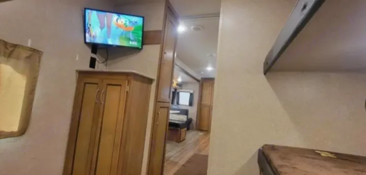 Spacious RV rental interior featuring bunk beds, a wall-mounted TV, and ample cabinetry in the living/kitchen area.. Coachmen Catalina 2019