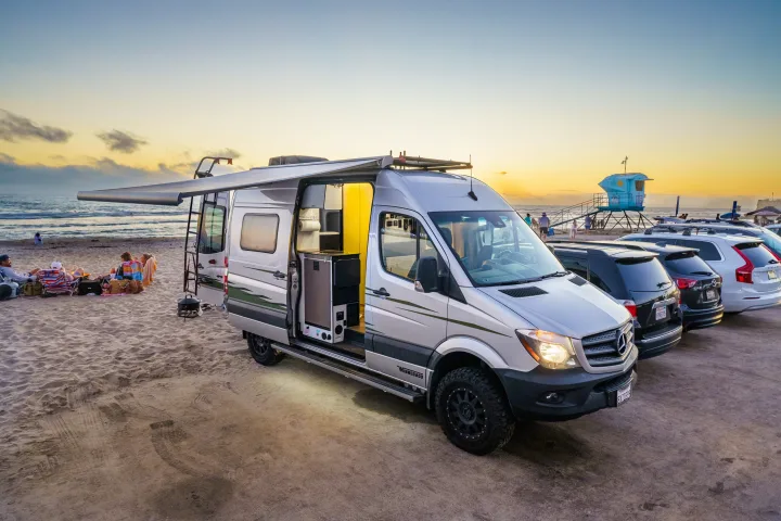 Enjoy beach sunsets with an RV rental! This silver camper van offers outdoor living by the ocean at dusk.. Winnebago Revel 2019