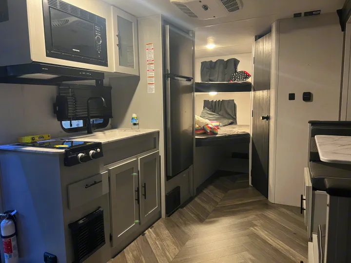 Modern RV rental interior with kitchen, bunk beds, and dinette. Functional and stylish living space for travelers.. Forest River Salem FSX 2022