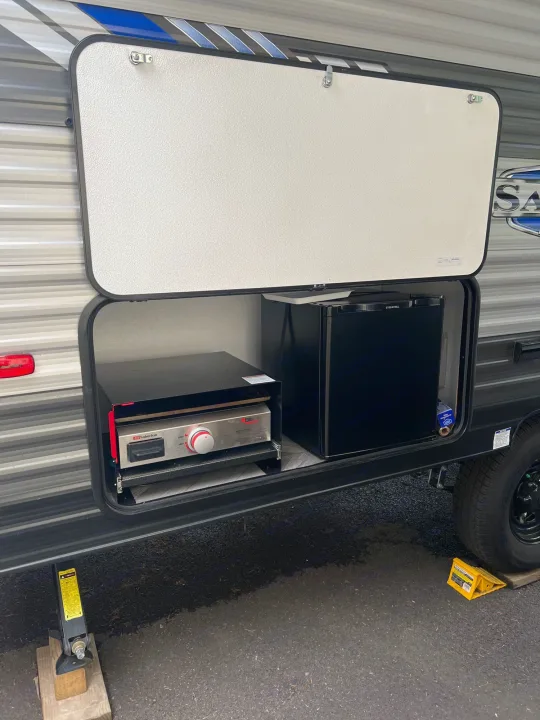 RV rental outdoor kitchen featuring a pull-out griddle and mini-fridge, ideal for al fresco cooking.. Forest River Salem FSX 2022