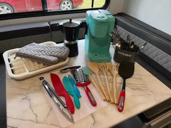 This RV rental kitchen is stocked with essentials: Keurig, Moka pot, dish rack, cutlery, knives, tongs, and cooking utensils.. Forest River Wildwood FSX Plantium 2022