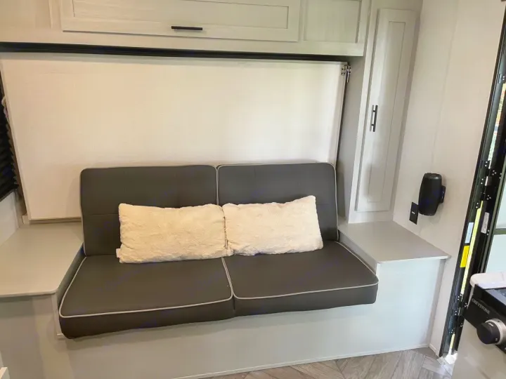 Comfortable RV rental interior with a versatile sofa, ready to convert into a bed, flanked by storage cabinets.. Forest River Wildwood FSX Plantium 2022