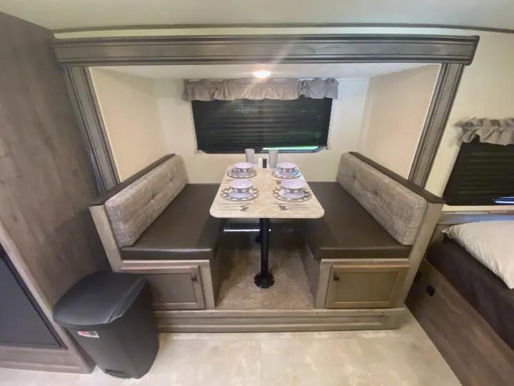 RV rental interior: A cozy dinette with bench seating, set table, and window blinds, perfect for on-the-road dining.. Coachmen Apex Nano 2021