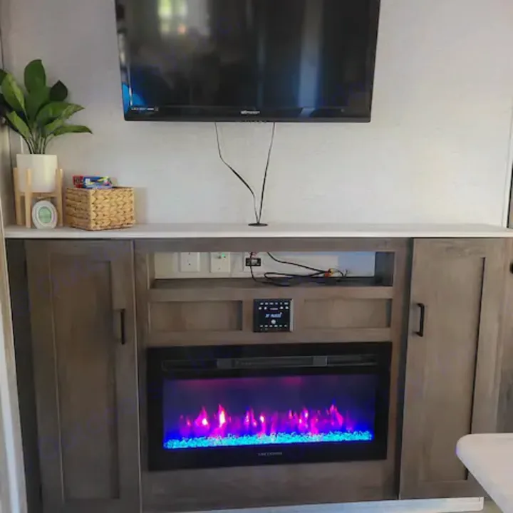 Cozy RV rental interior featuring a flat-screen TV, electric fireplace with colorful flames, and built-in storage. Perfect for road trips.. Forest River Salem Cruise Lite 2022