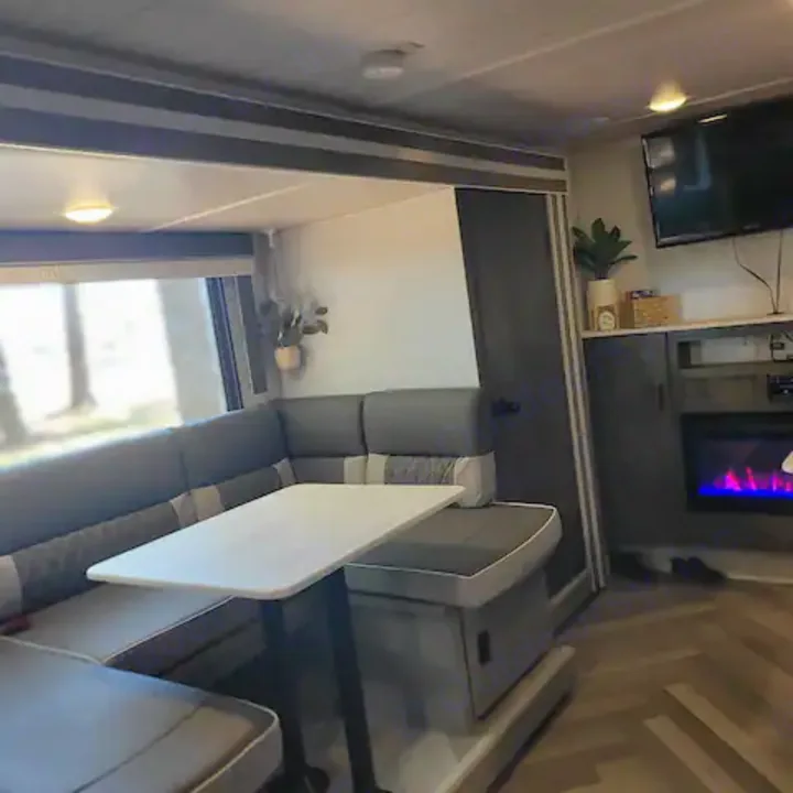 Explore this modern RV rental's inviting interior, featuring an L-shaped dinette, large window, and fireplace.. Forest River Salem Cruise Lite 2022