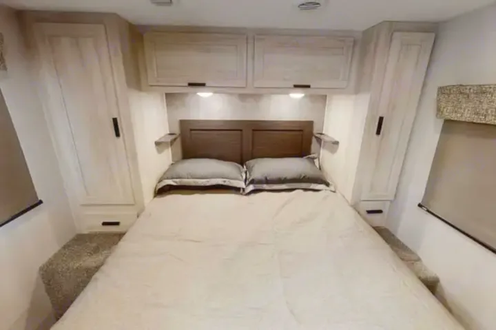 RV rental bedroom with bed, headboard, overhead cabinets, and side wardrobes for your travels.. Forest River Sunseeker LE 2021