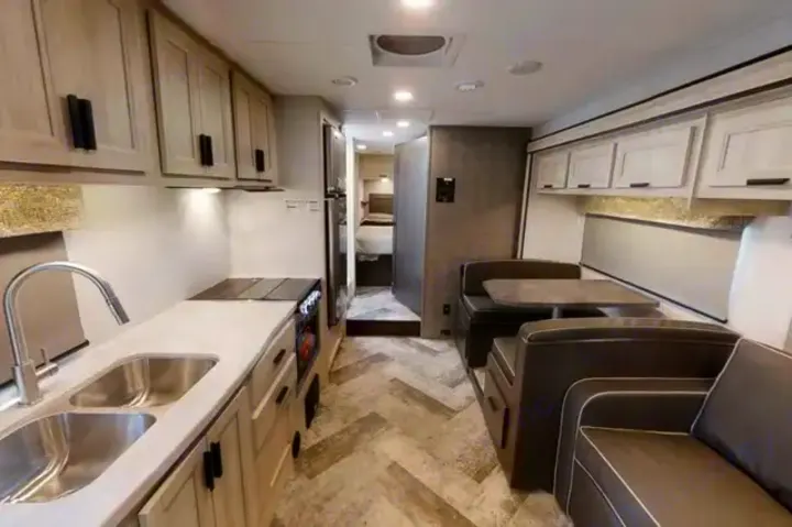 Explore this modern RV rental interior with a bright kitchen, spacious dinette, comfortable lounge, and private bedroom.. Forest River Sunseeker LE 2021