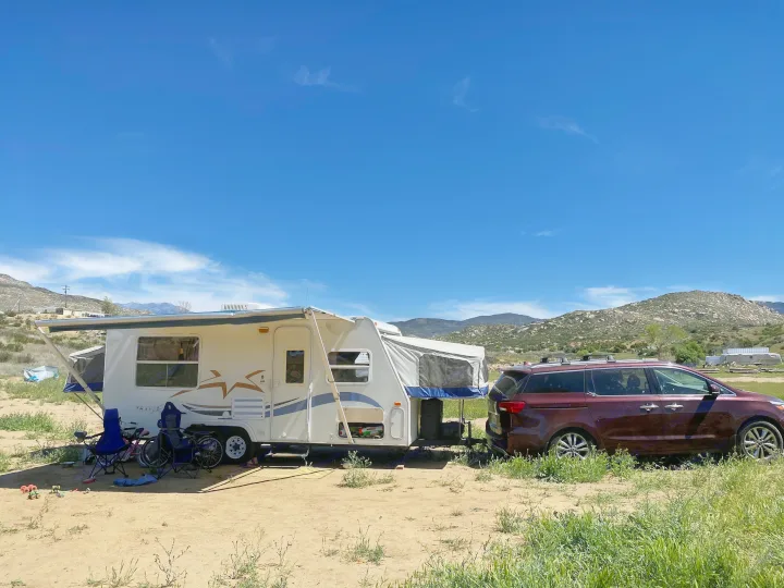 An rv rental hybrid camper and minivan parked at a sunny, mountainous outdoor campsite. Blue sky overhead.. Starcraft Travel Star 2002