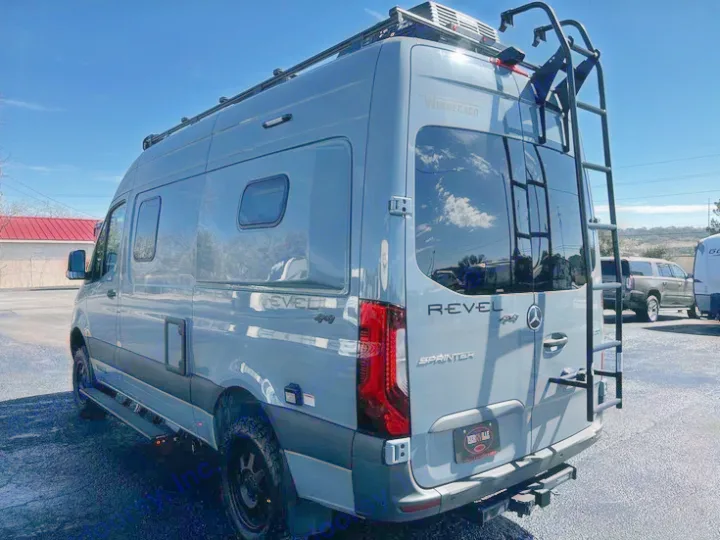 Gray Winnebago Revel 4x4 Sprinter RV rental parked. Features roof rack, ladder, and all-terrain tires for adventure.. Winnebago Revel 2022