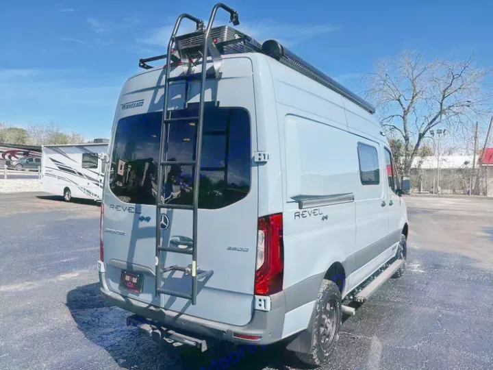 A light grey Winnebago Revel 4x4 Sprinter van, with roof rack/ladder and awning, perfect for an adventurous rv rental.. Winnebago Revel 2022