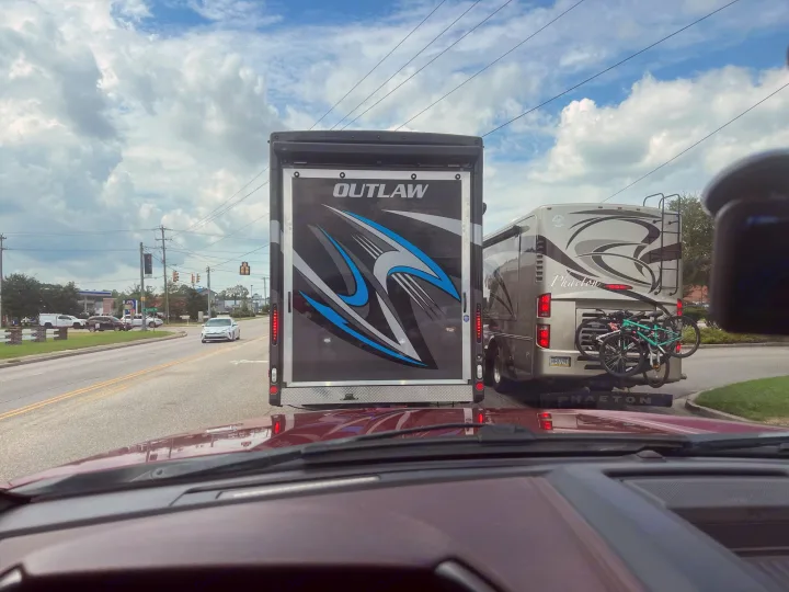 From a car, two RVs are seen: an Outlaw toy hauler and a Phaeton with bikes. Great for an RV rental trip!. Thor Outlaw 2022