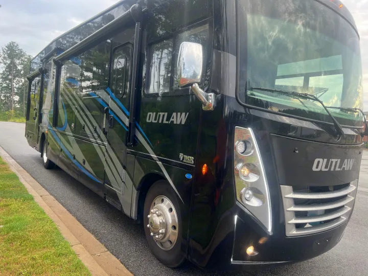 Black Thor Outlaw motorhome, a modern rv rental with blue/grey graphics, parked on pavement.. Thor Outlaw 2022