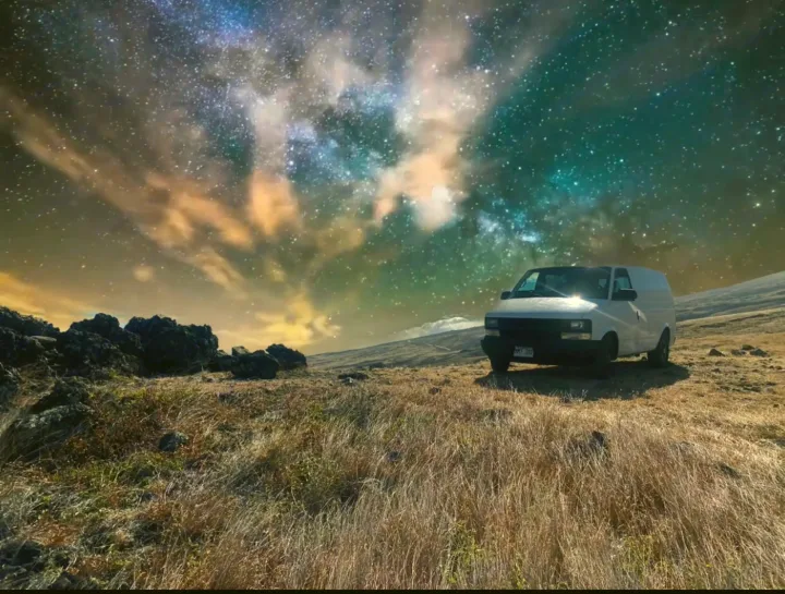Adventure under the stars! A white van (perfect RV rental) is parked on a rocky, grassy hill under a breathtaking Milky Way night sky.. Chevrolet Other 2005