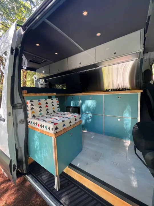 Bright, custom camper van interior: teal cabinets, wooden counters, colorful seating, and kitchen. Perfect for RV rental.. Mercedes Sprinter 2016