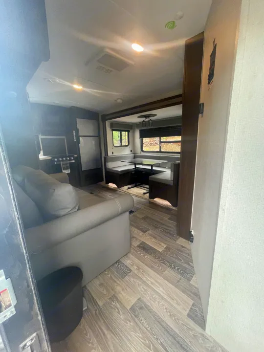 This RV rental offers a spacious interior, featuring a comfy sofa, compact kitchen, and a dinette with large windows.. Keystone RV Springdale 2020